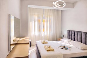 A modern hotel room with a large bed, a bedside table, a mirror, and a window with sheer curtains. - Happy Stay Apartment By The Sea 092, Durres, Albania (Durres)