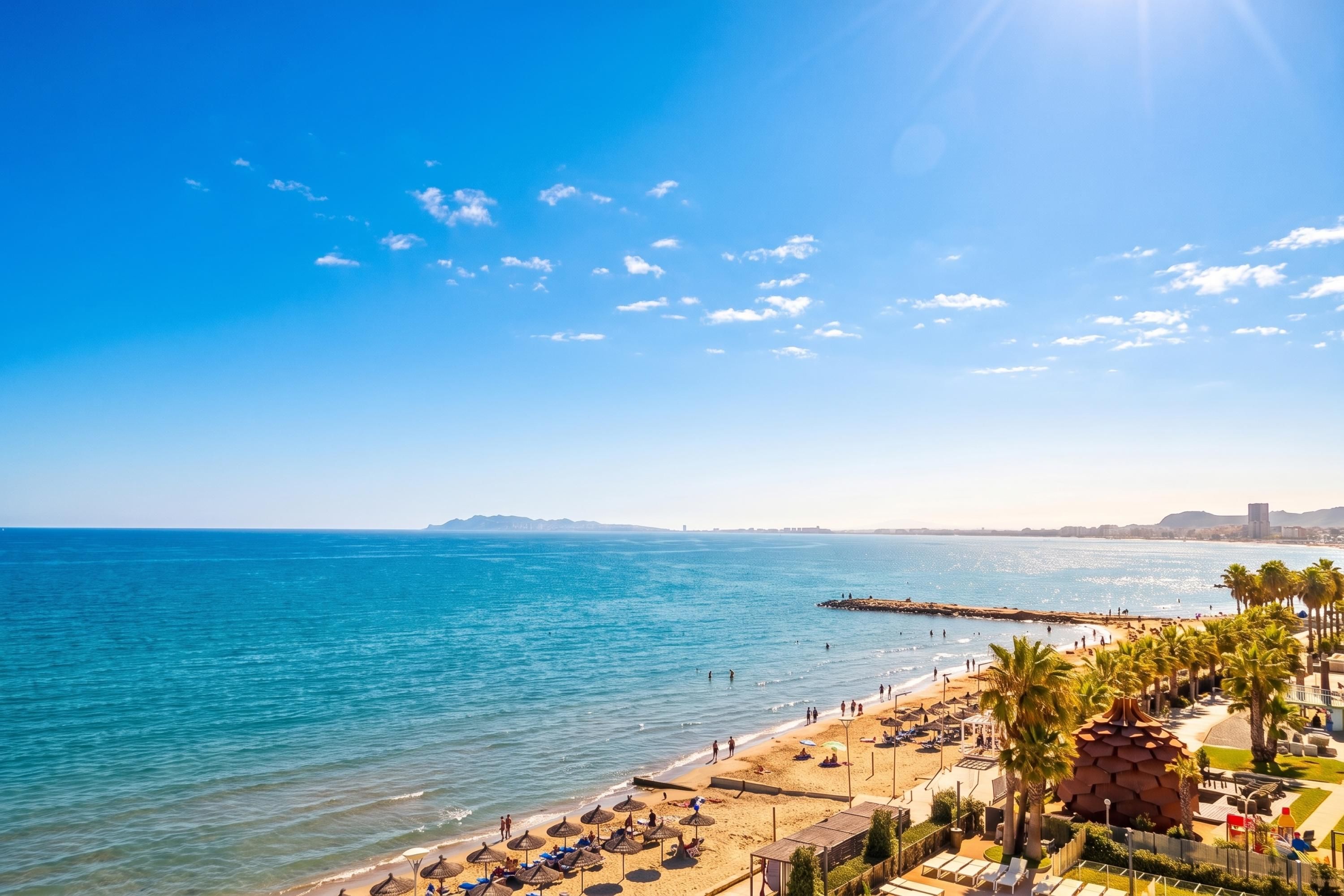 A beach with clear skies, calm sea, and a sandy shore with umbrellas and lounge chairs.