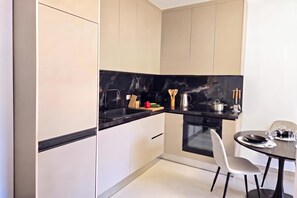 A modern kitchen with a black countertop, white cabinets, and a built-in oven. - Happy Stay Apartment By The Sea 092, Durres, Albania (Durres)