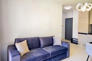 A modern living room with a dark-colored sofa, two cushions, and a unique light fixture. - Happy Stay Apartment By The Sea 092, Durres, Albania (Durres)
