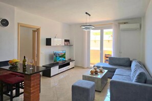 A modern living room with a grey sofa, a coffee table, a TV, and a dining area with a bar. - Sea View Holiday Apartment 073, Durres, Albania (Durres)