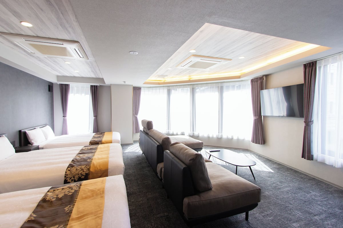 A hotel room with a large bed, a sofa, a small table, and a TV.