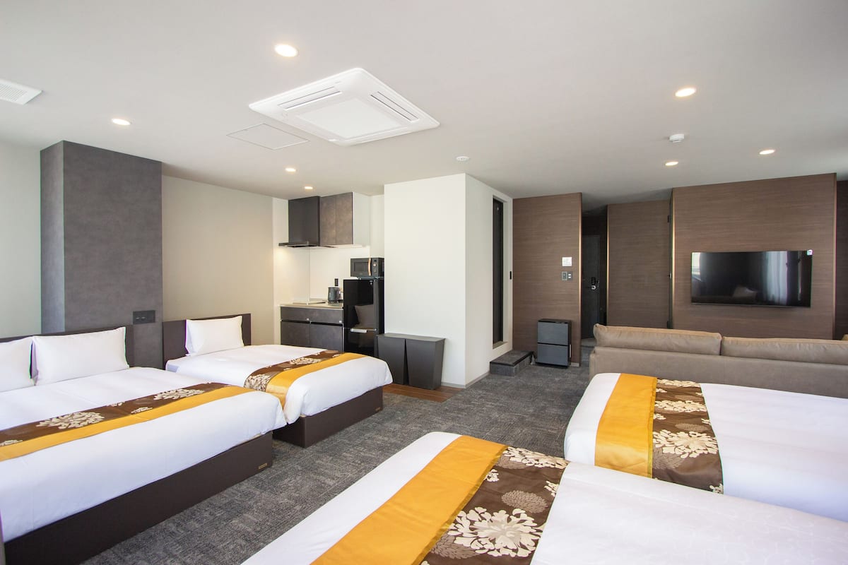 A hotel room with two beds, a sofa, a TV, a microwave, and a small desk.