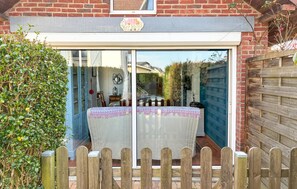 Eine Terrasse mit einem Tisch, der mit einer weißen Tischdecke bedeckt ist, und einem Holzzaun im Vordergrund.