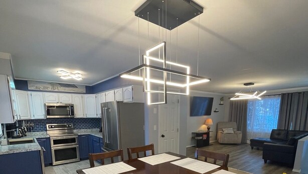 Een moderne keuken met inbouwapparatuur, een eethoek met een grote tafel, en een woonkamer met een bank en een televisie.