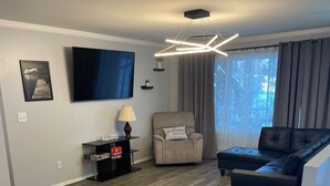 Een moderne woonkamer met een flatscreen televisie, een bank, een fauteuil en een salontafel.