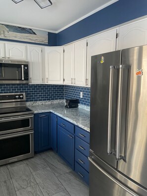 A kitchen with white cabinets, a stainless steel refrigerator, a microwave, and a toaster. - Green Aurora: 3 bed, 2 bath,  Laundry, King Bed (Fairbanks)