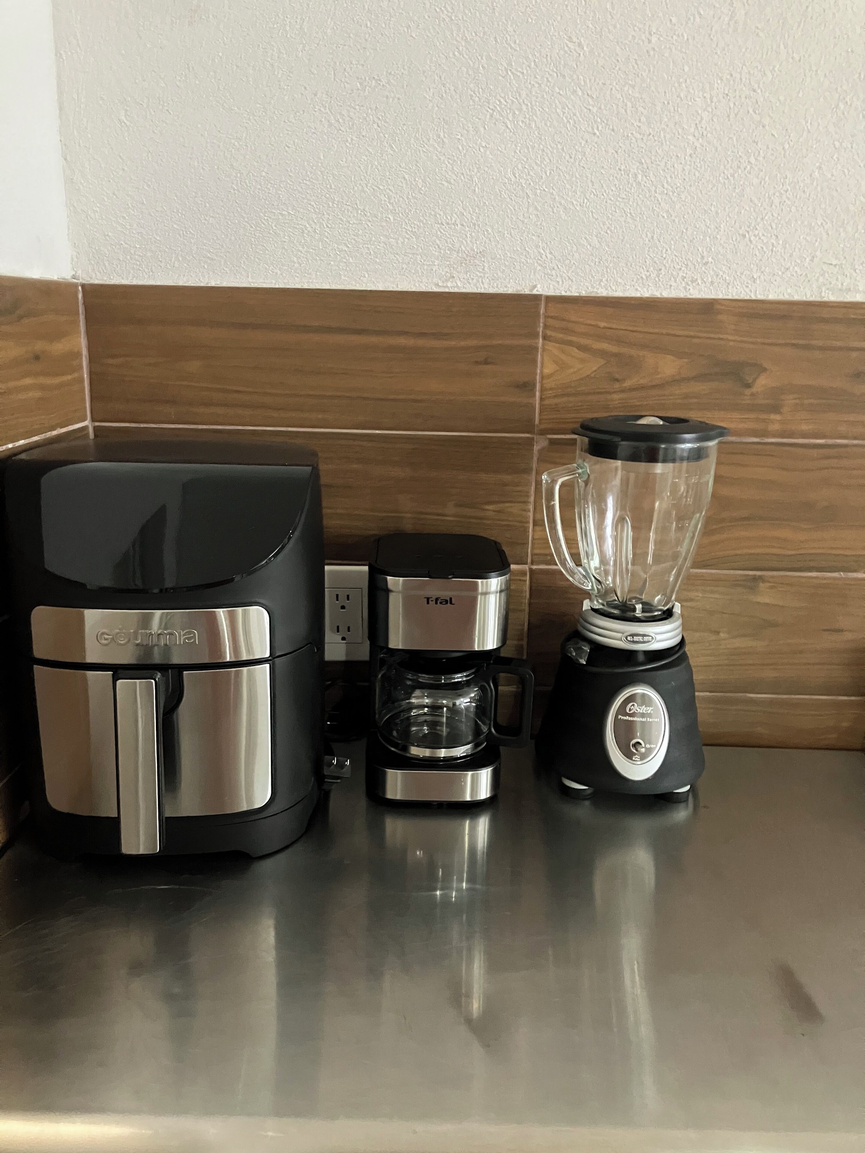 Uma bancada de cozinha com cafeteira, liquidificador e torradeira.