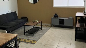 Una sala de estar con sofá, mesa de centro y mueble para televisor.