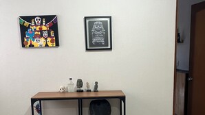 Una habitación con una mesa de madera y dos estanterías, un cuadro en la pared y una puerta que da a otra habitación.