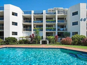 Ein modernes Hotel mit Schwimmbad, mehreren Balkonen und einem gepflegten Garten.