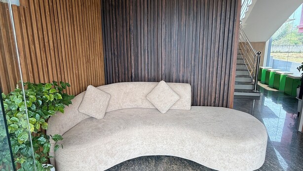 Een modern interieur met een gebogen bank, houten paneelwanden en een glazen vloer.