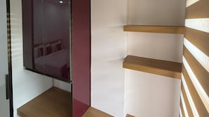 Een moderne kamer met een houten plank, een spiegelkast en een kleine prullenbak.