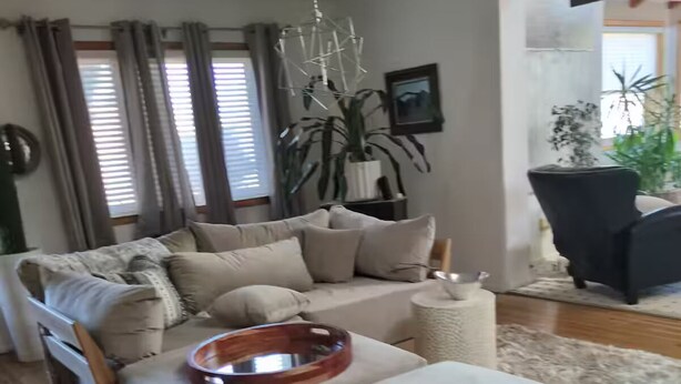 Un salon avec un canapé, un pouf et un vase décoratif posé sur le sol.