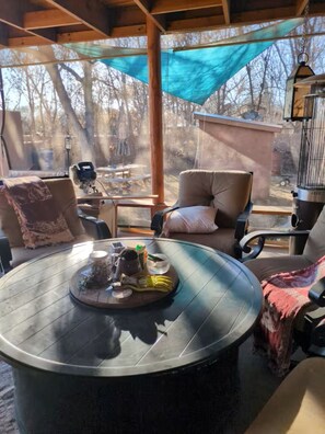 A round table with a tray of food, a chair with a cushion, and a view of trees through a window. - Beautiful Espanola influenced. (Española)