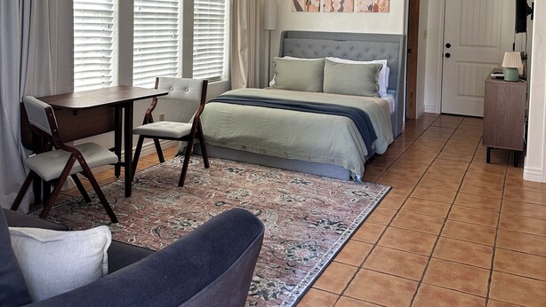 Un dormitorio con cama, escritorio, silla, ventilador de techo y puerta.