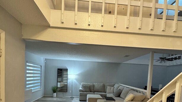 Un vaste espace de vie doté d’un plancher en bois, d’un grand canapé d’angle et d’un escalier menant à l’étage supérieur.