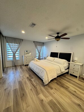 A bedroom with a bed, nightstands, a ceiling fan, and a window with curtains. - Spacious & Clean Home for 6 – Small Patio & Garage (Houston)