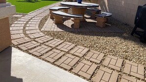 Un espace patio aménagé avec un ensemble de sièges disposés en cercle, un palmier et une petite table surmontée d’un pot bleu.