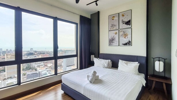 Ein Hotelzimmer mit einem großen Bett, Blick auf die Stadt und Kunstwerken an der Wand.
