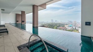 Ein moderner Infinity-Pool mit Blick auf die Stadt, einem klaren Himmel und einem Schild, das eine Höhe von 1,2m anzeigt.