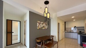 Ein Essbereich mit Holztisch und Stühlen, einer modernen Pendelleuchte und einem farbenfrohen abstrakten Gemälde an der Wand.