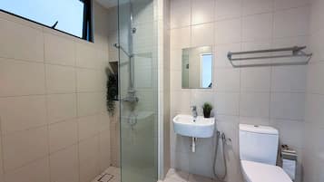 A modern bathroom with a glass-enclosed shower, a white sink, and a toilet.