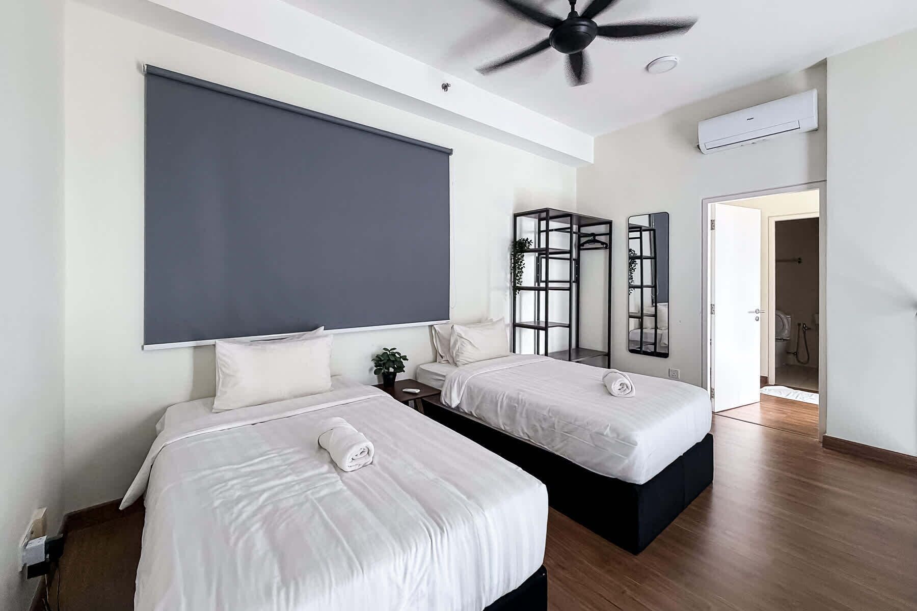 A modern hotel room with two beds, a ceiling fan, an air conditioning unit, and a large mirror.