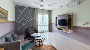 A modern living room with a sofa, a coffee table, a TV, and a ceiling fan. - Family 2BR Apartment, Melaka City (Malacca City)