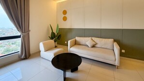 A modern living room with a sofa, a small table, and a potted plant. - Modern 2BR Stay, Near Jonker St Melaka (Malacca City)