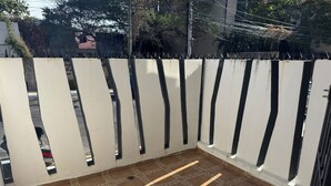 Ein Balkon mit Fliesenboden und einem weißen Zaun mit vertikalen Schlitzen.