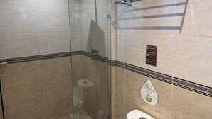Ein modernes Badezimmer mit Duschkabine aus Glas, Toilette und Handtrockner.