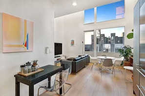 Ein zeitgemäßer Wohnraum mit Essbereich, einer Couch und einem großen Fenster mit Blick auf eine Stadtlandschaft.