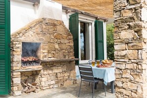 A stone-built outdoor grill with a table and chairs nearby. - Independent villa with A/C | V05 (Imperia)
