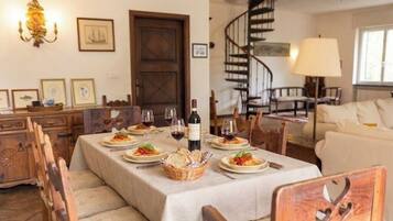 A dining area with a table set for a meal, chairs, a chandelier, a staircase, and a sofa.
