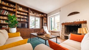 Ein Wohnzimmer mit Kamin, Bücherregalen, einer Couch und einem Couchtisch.