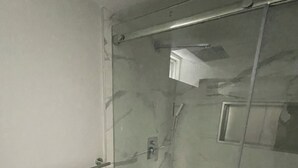 Un espace douche fermé par des parois en verre, doté d’une poignée en métal et d’une petite étagère.