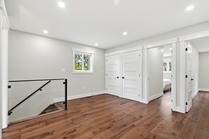 A spacious room with hardwood flooring, white walls, and a large closet with sliding doors.