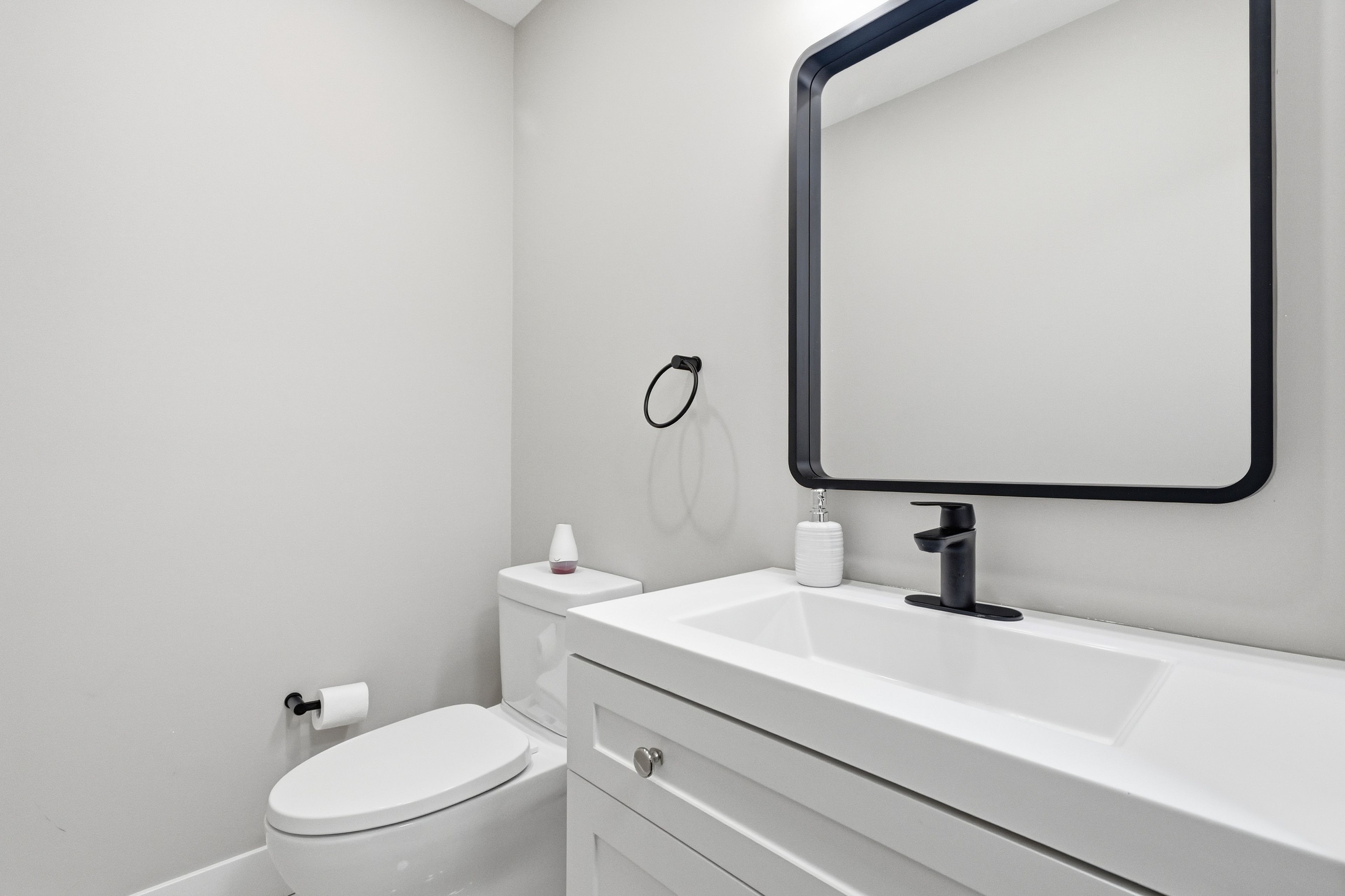 A modern bathroom with a toilet, sink, and mirror.