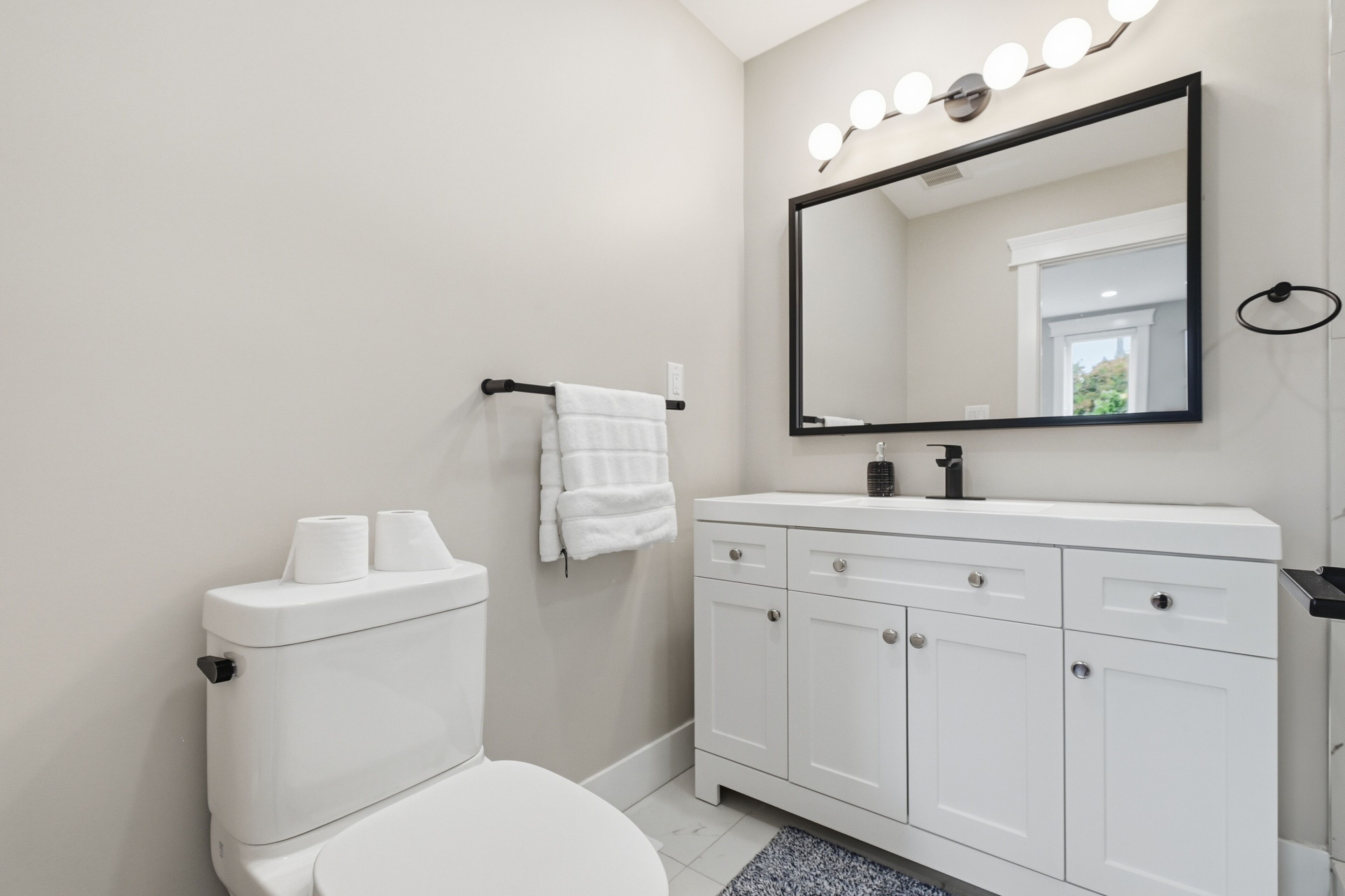 A bathroom with a toilet, a sink with a mirror, and a towel rack.