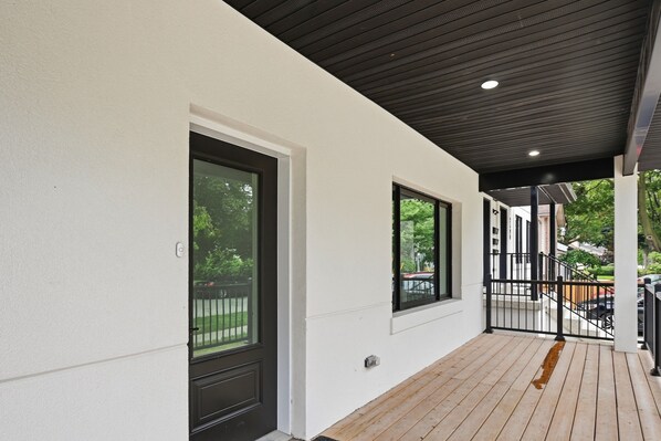 A modern building exterior with a wooden deck, a black door, and large windows.