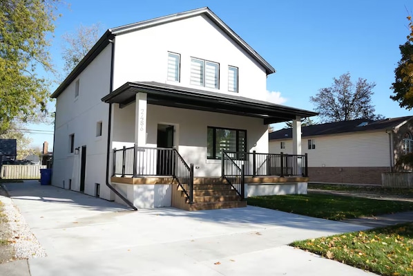A two-story house with a front porch, a garage, and a visible address number.
