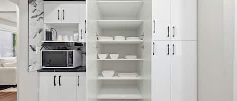 A modern kitchen with white cabinetry, a built-in microwave, and a coffee maker.