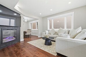 A modern living room with a fireplace, a sofa set, and a dining area.