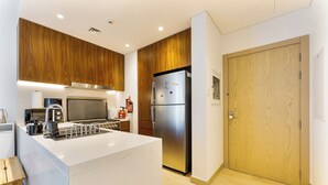 Una cocina moderna con armarios de madera, un refrigerador de acero inoxidable y una encimera blanca.