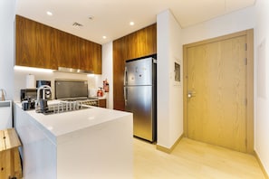 A modern kitchen with wooden cabinets, a stainless steel refrigerator, and a white countertop. - Chic 2-Bed Apartment with Balcony and Waterfront Views in Port de La Mer (Dubai)