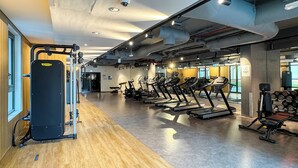 Un gimnasio con equipo cardiovascular, máquinas de pesas y suelo de madera.