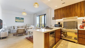 Una cocina moderna con armarios de madera, horno integrado y zona de comedor con sofá y mesa.