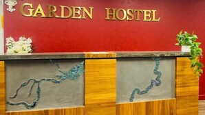 A reception desk with a red wall and the words 'GARDEN HOSTEL' in gold letters. - Garden Hostel (Auckland)