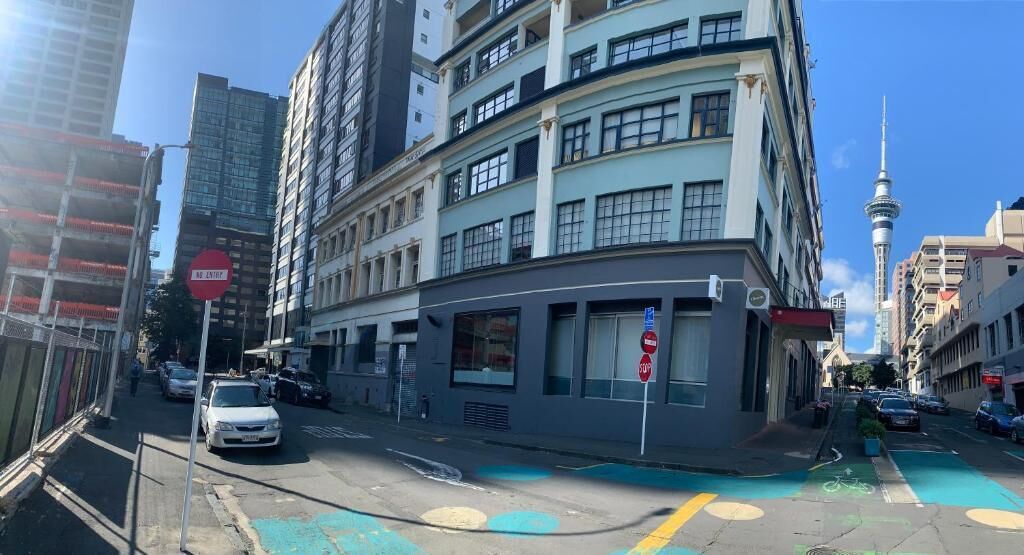 A multi-story building with a 'No Entry' sign, a bike lane, and a view of a tower in the background.